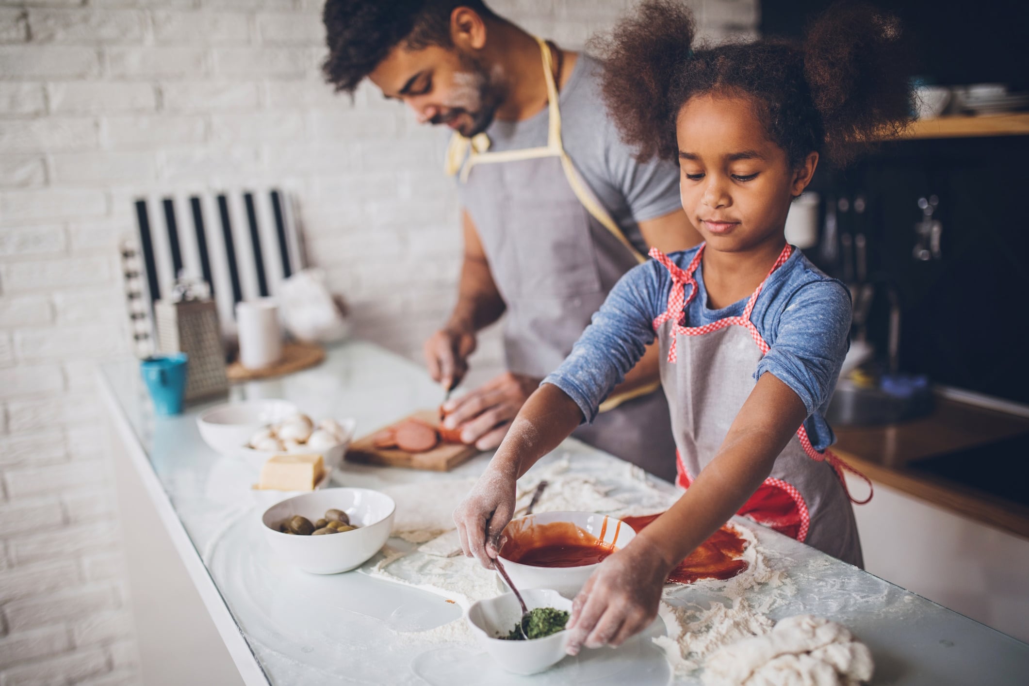 Father and daughter making pizza at home