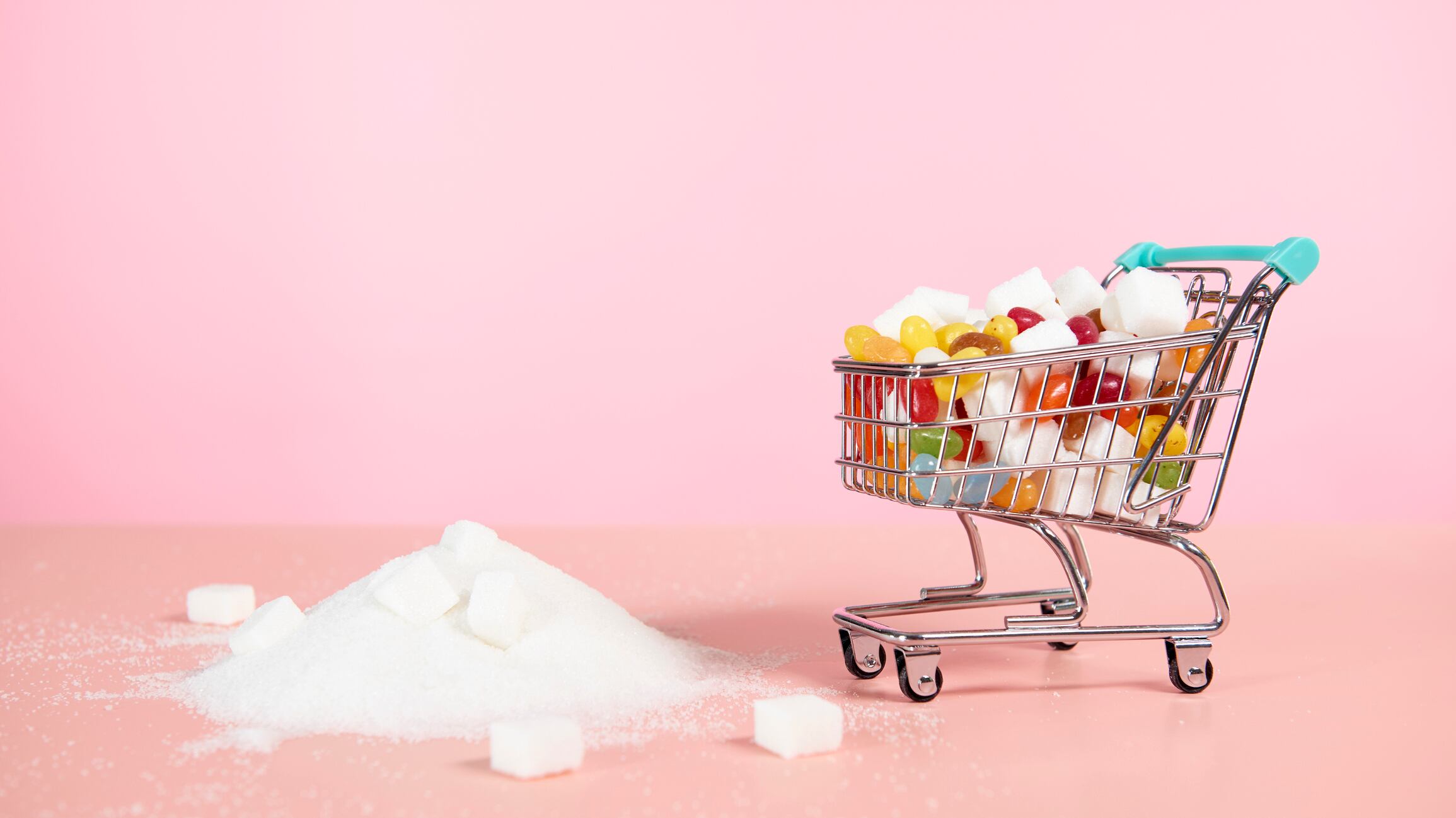 Supermarket trolley with sweets and pile of sugar next to it