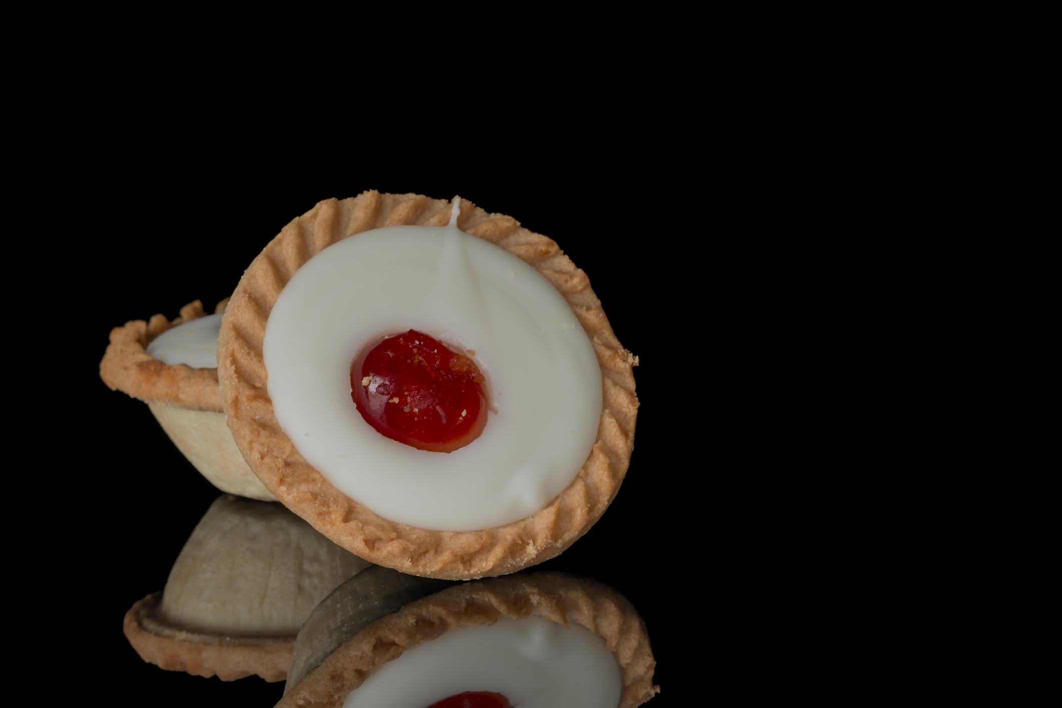 Iced cherry bakewell tart on black background ANA LEBIODIENE GettyImages