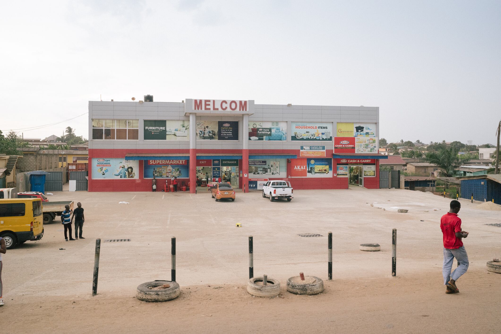 Cape Coast, Ghana - 19 Februar 2022: Everyday street scenes in Tema, wider region of Accra, a male pedestrian walks by a Melcom supermarket