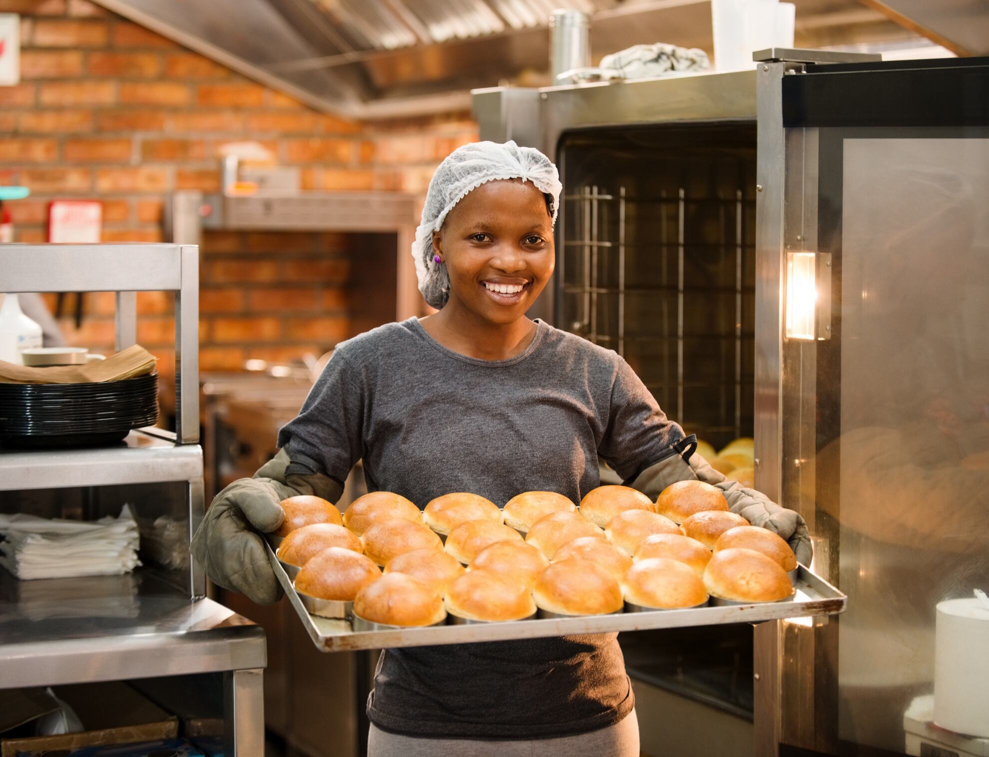 Female baker with tray of burger buns