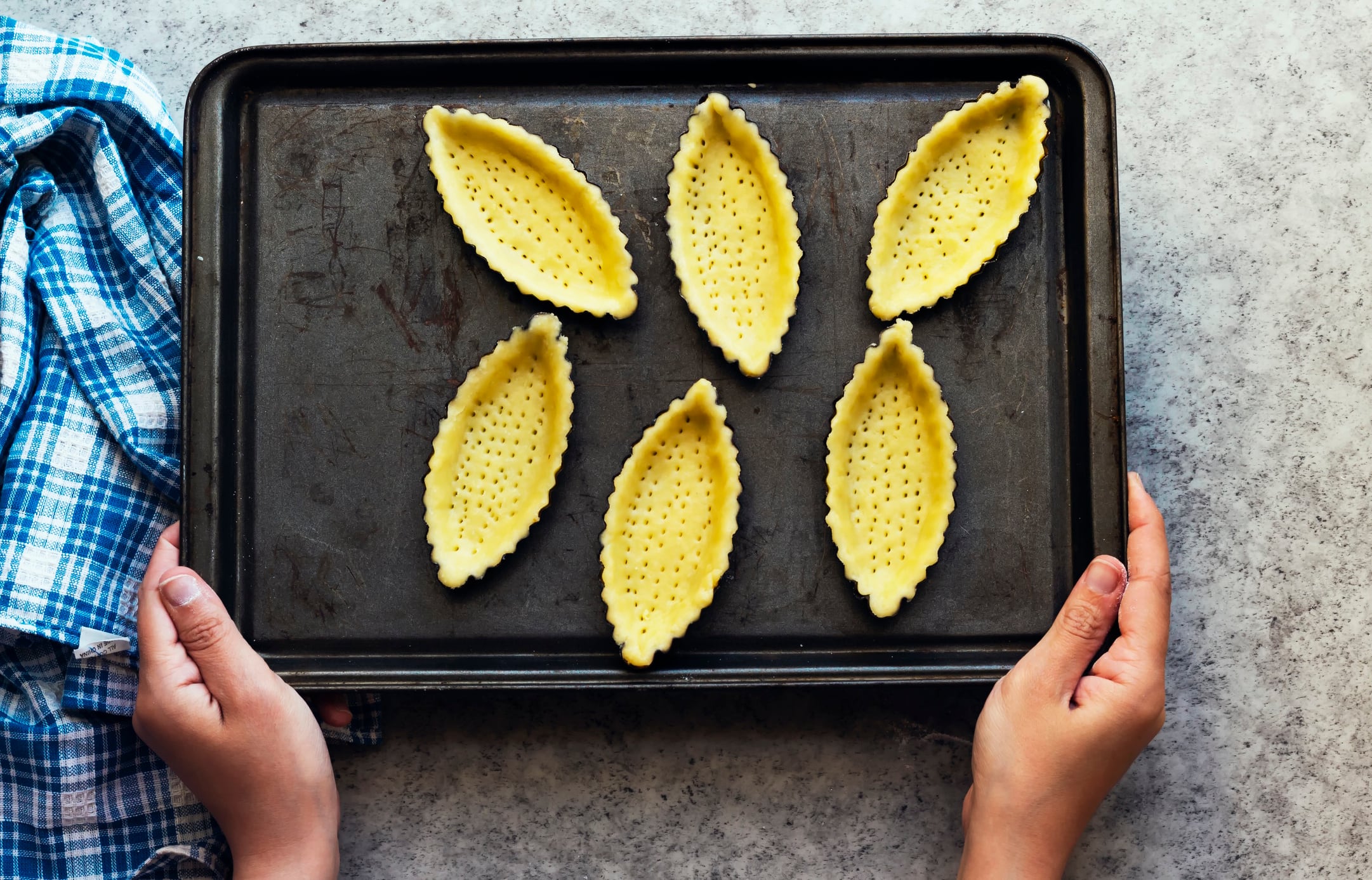 Woman's hand holding a tray of empty tartlets ninitta GettyImages