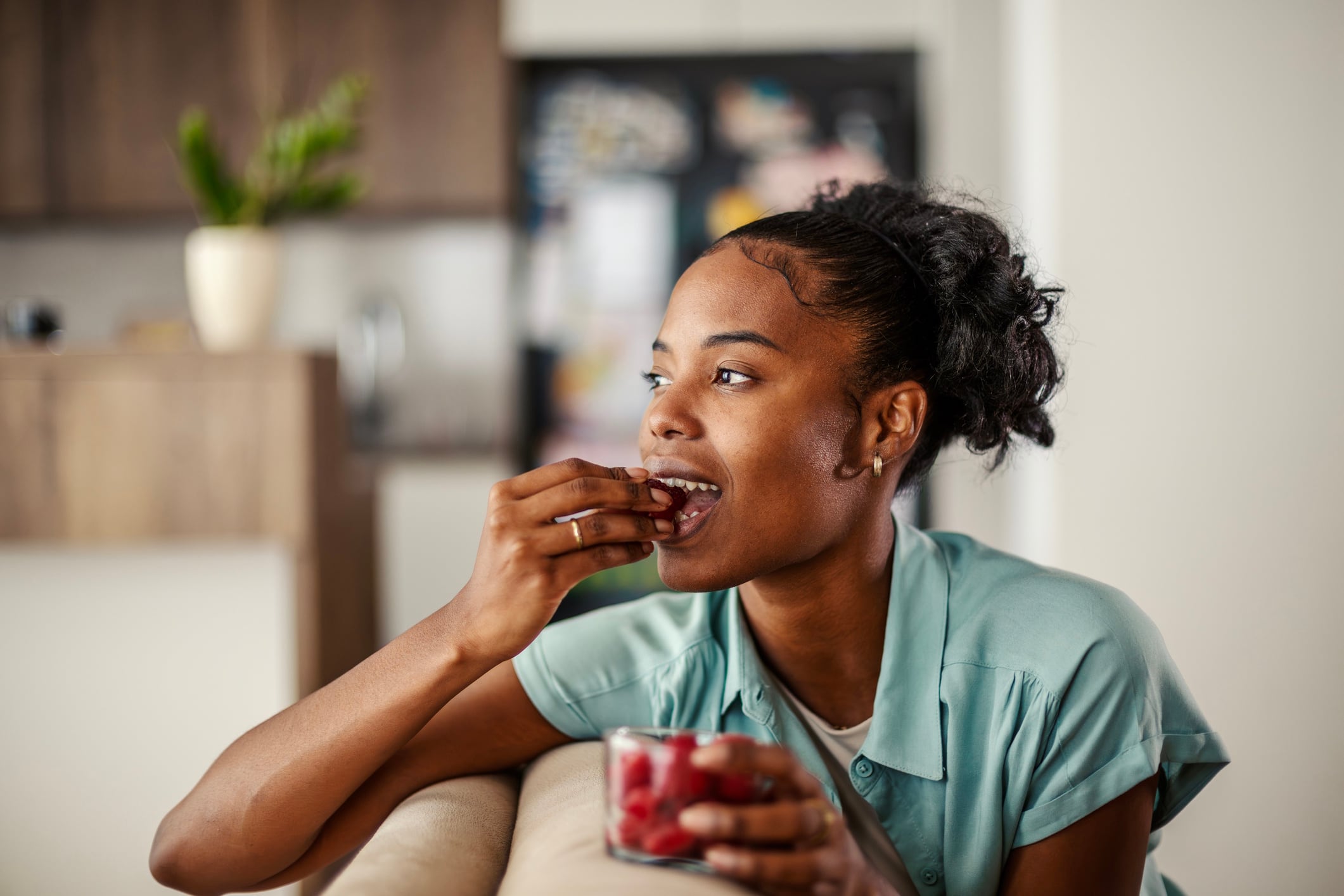 Young woman snacking at home on raspberries Organic Media GettyImages-