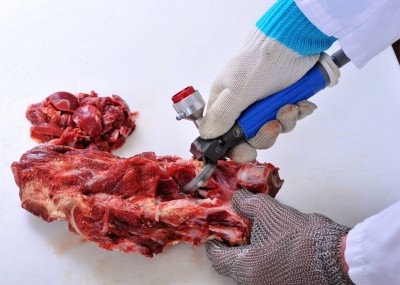 An employee trims meat from beef bones with Bettcher's Whizard trimmer.