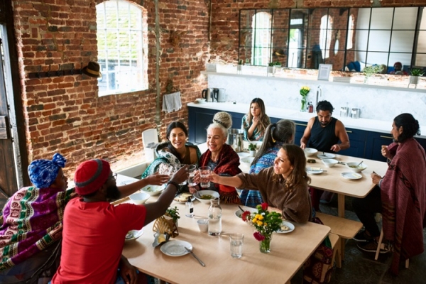 Community food, multiracial people around a table sharing a meal Getty